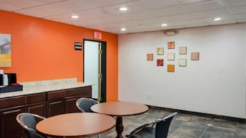 A hotel lobby with two round tables, a counter, and a wall with framed pictures.
