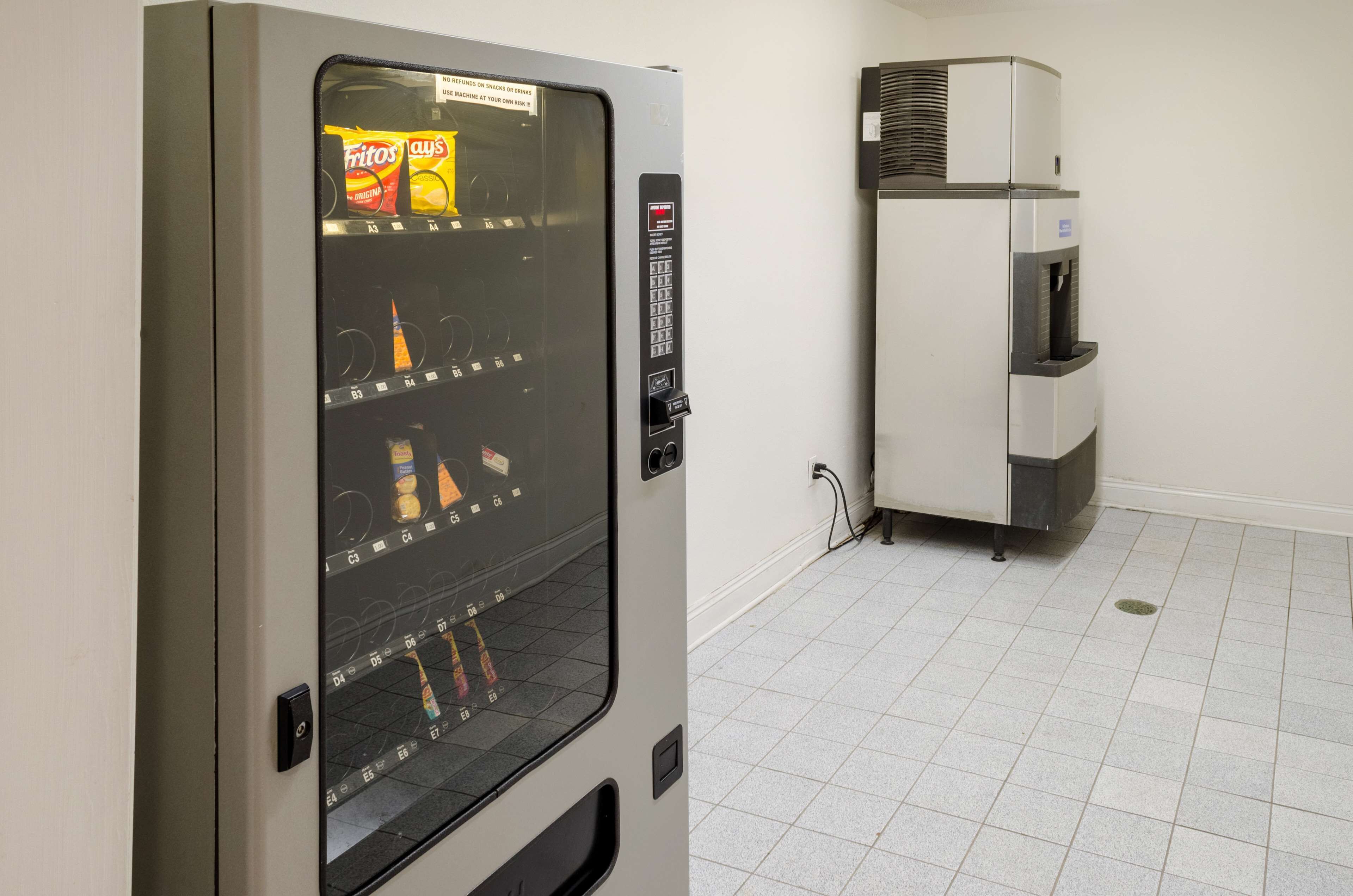 A vending machine with a selection of snacks and a water dispenser in a clean, tiled room.