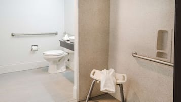 Casa de banho com sanita, barra de apoio e suporte para toalhas.
