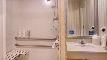 A bathroom with a shower, a sink, and toiletries.