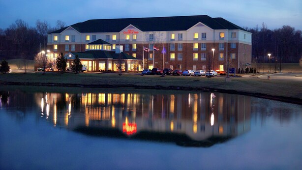 A hotel with multiple floors, a parking lot, and a body of water in front.