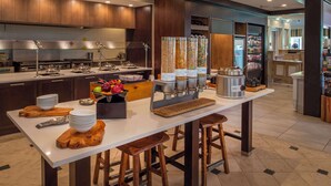 A modern kitchen with stainless steel appliances, a central island with stools, and a wine cooler.
