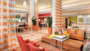 A spacious lobby with a seating area, a reception desk, and a kitchen area.