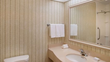 A bathroom with striped wallpaper, a toilet, a sink with a mirror, and two towels hanging on the wall.