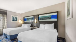 A hotel room with two beds, a nightstand, and a wall-mounted TV.