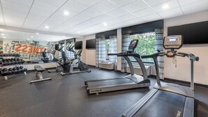 A gym with treadmills, dumbbells, and a wall with motivational words.