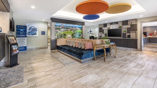 A modern lobby with a blue sofa, a reception desk, and a large cityscape painting.