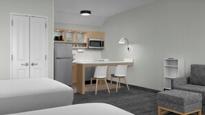 A compact hotel room with a kitchenette, a desk with two chairs, a sofa, and a bed. - TownePlace Suites by Marriott Annapolis (Annapolis)