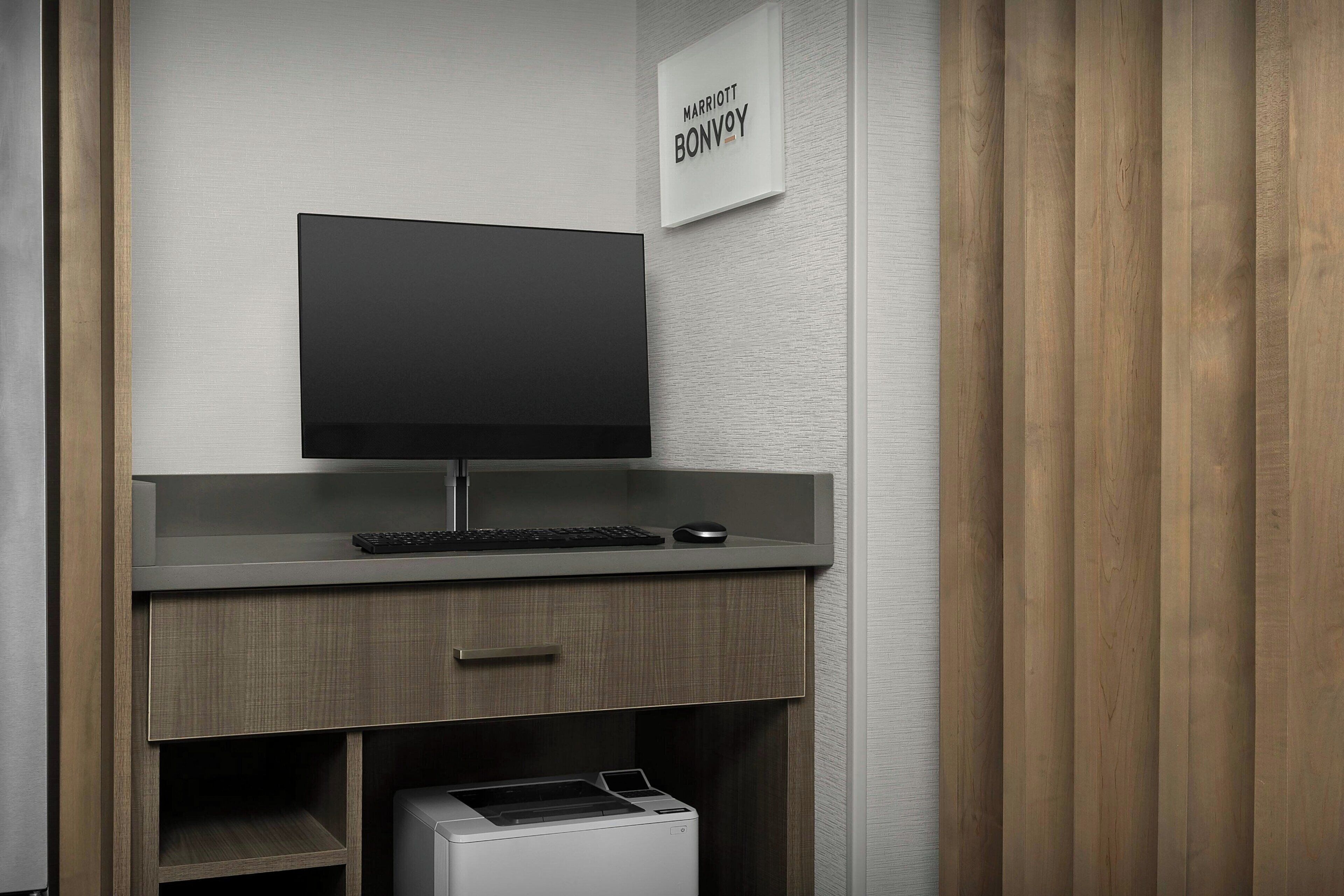 A modern office desk with a flat-screen monitor, keyboard, and mouse.