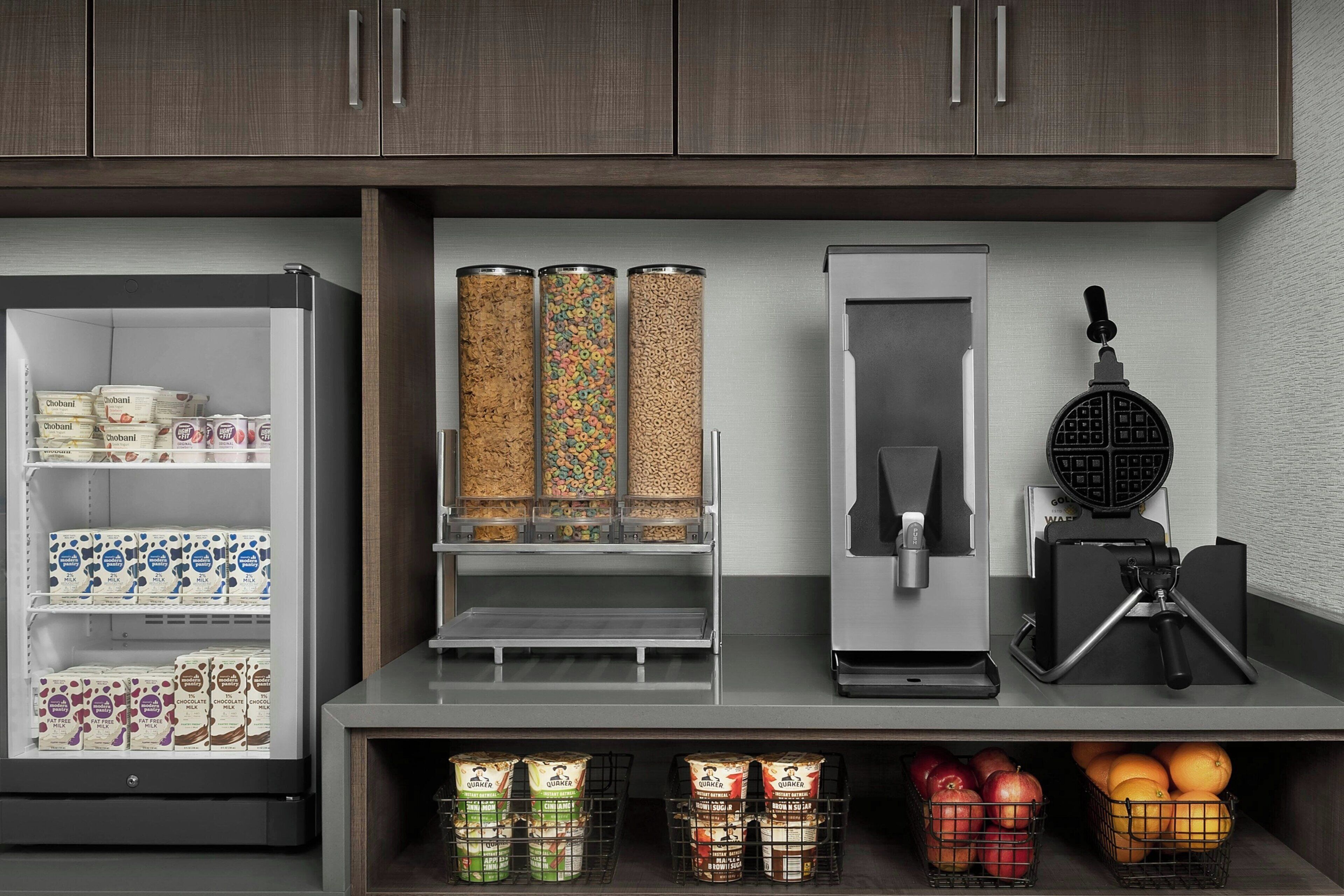 Une cuisine équipée d’un réfrigérateur rempli de produits laitiers, d’une machine à café et d’un appareil à gaufres.