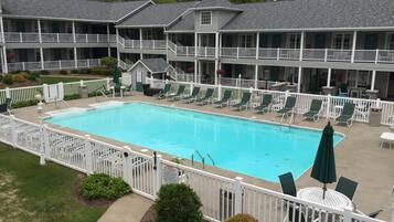 A hotel with a swimming pool, multiple balconies, and outdoor seating areas.