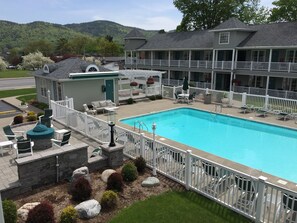 A hotel with a swimming pool, outdoor seating, and a view of the mountains.