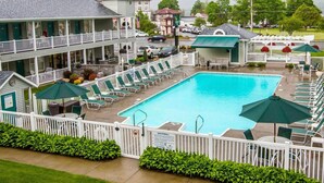 A hotel with a swimming pool, multiple lounge chairs, and a white fence surrounding the area. - Quality Inn Lake George (Lake George)
