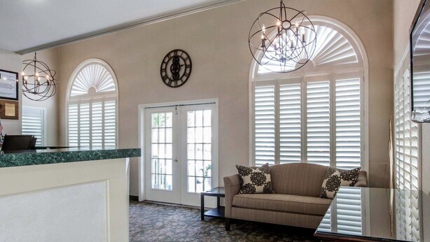 A spacious living area with a sofa, a chandelier, and a clock on the wall. - Quality Inn Lake George (Lake George)