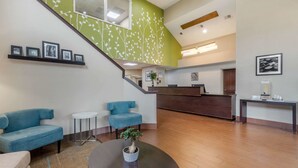 A reception area with a staircase, reception desk, and seating area with blue sofas. - Sleep Inn Orangeburg (Orangeburg)