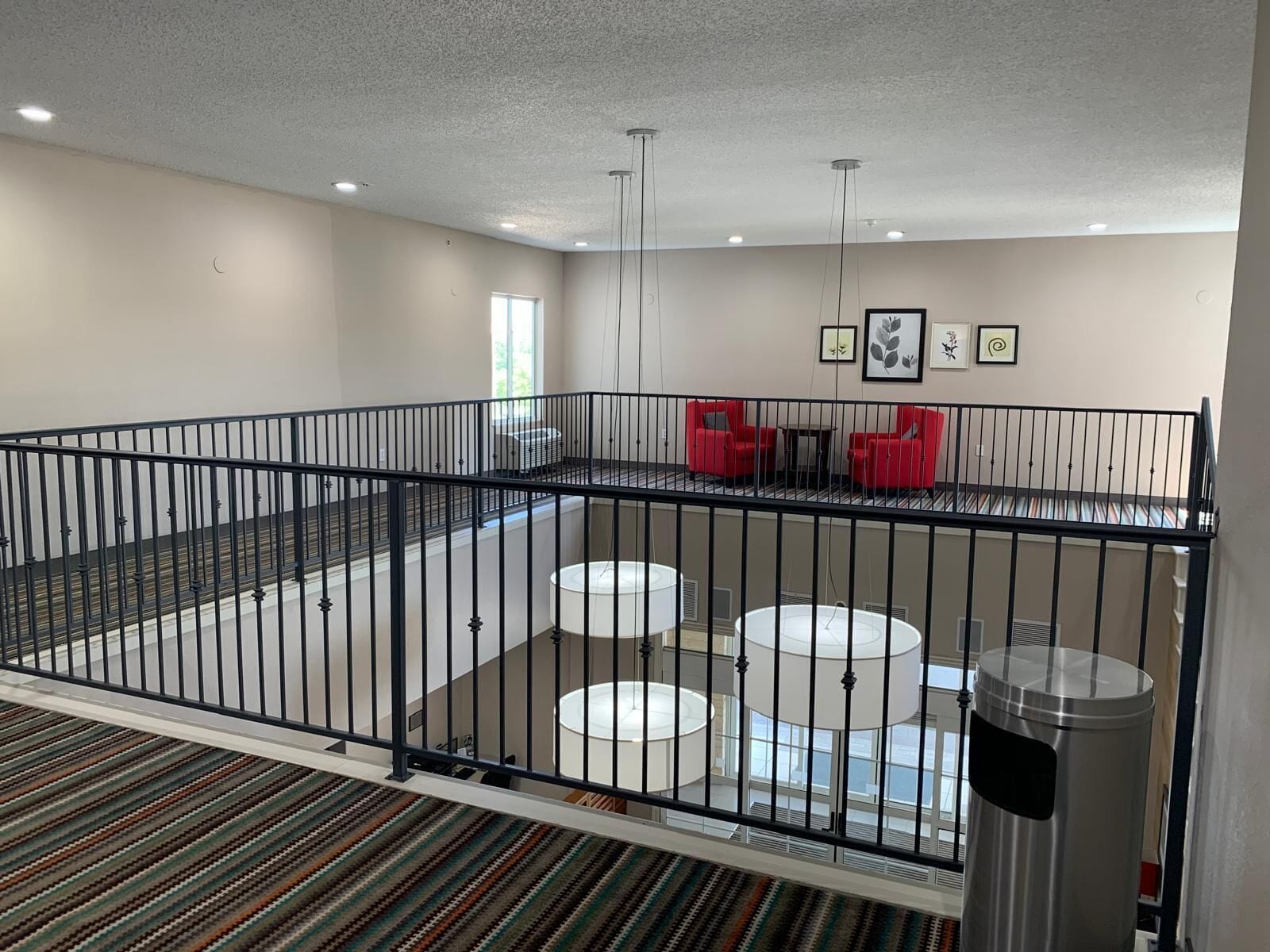 A spacious room with a balcony, a seating area with red chairs, and a large window.