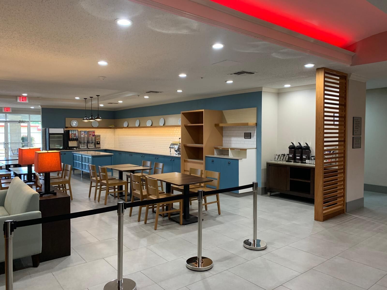 A modern restaurant with a blue and white color scheme, featuring a kitchen area, dining tables, and a bar.