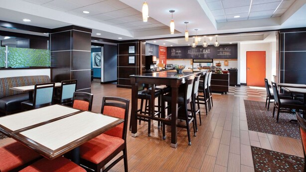 A modern restaurant with a long counter, multiple tables, and a bar area. - Hampton Inn Cincinnati-Northwest/Fairfield (Fairfield)
