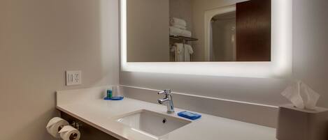 Un baño moderno con un lavabo blanco, un espejo y un perchero para toallas.