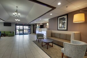 Um hall de entrada com balcão de recepção, um sofá, cadeiras e um lustre.