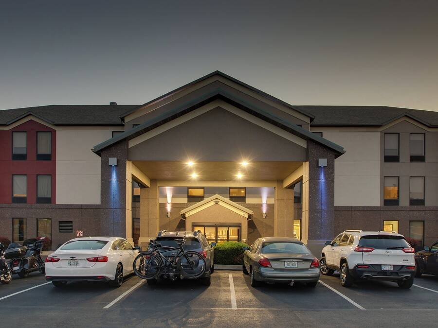 A hotel entrance with a parking lot, a covered area, and a building facade.
