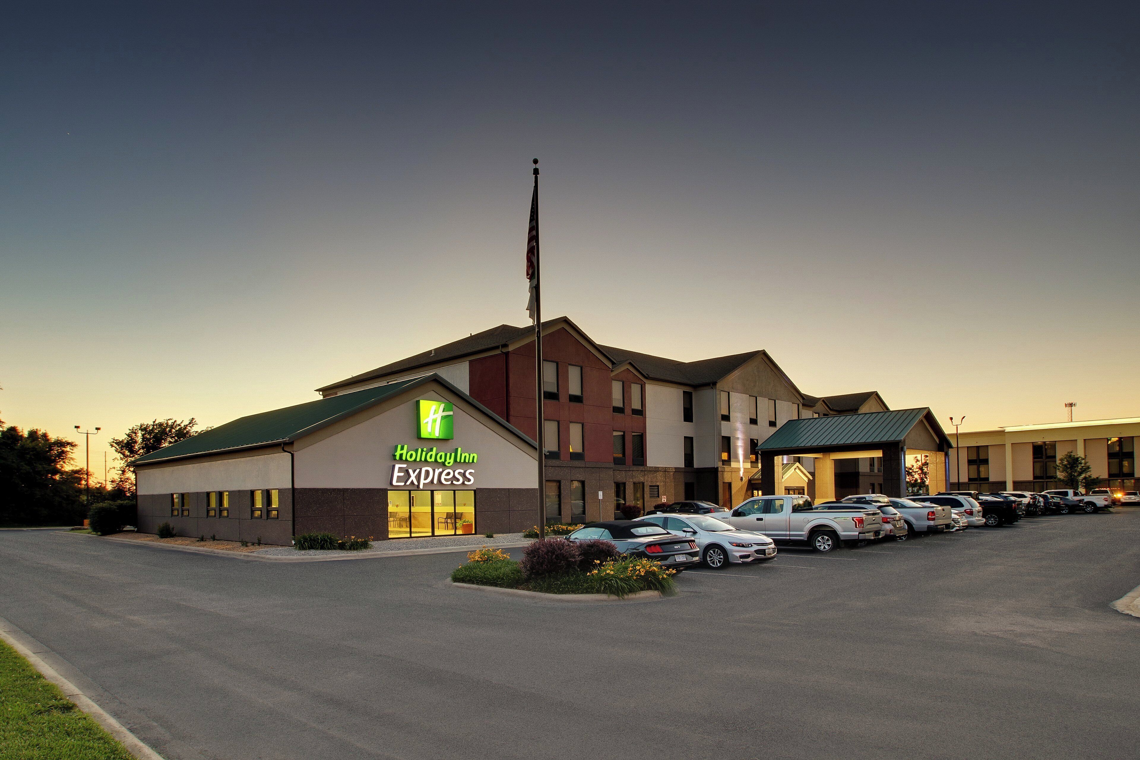 Edificio de Holiday Inn Express con un estacionamiento lleno de coches.