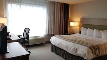 A hotel room with a bed, desk, chair, and a window with curtains.