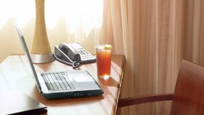 A hotel room with a wooden desk, a laptop, a telephone, and a glass of orange juice. - Country Inn & Suites by Radisson, Elk River, MN (Elk River)