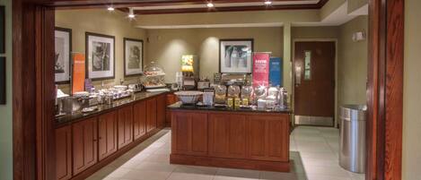 A buffet area with a wooden counter, various food items, and condiment stations.