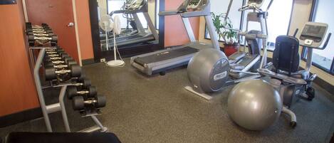 A gym with treadmills, a stationary bike, a rowing machine, and free weights.