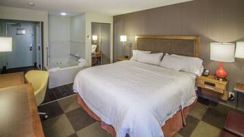 A hotel room with a large bed, a separate bathroom with a bathtub, a desk, and a chair.