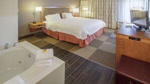 Habitación de hotel con una cama grande, baño independiente con bañera, escritorio con computadora y televisión.