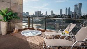 A balcony with a hot tub, lounge chairs, and a city view. - Leonardo Plaza City Tower (Ramat Gan)