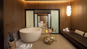 A modern bathroom with a large bathtub, a vanity, and a seating area. - Leonardo Plaza City Tower (Ramat Gan)