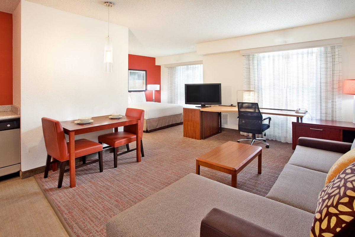 Ein Hotelzimmer mit Essbereich, Fernseher, Schreibtisch und einer Couch.