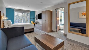 A modern hotel room with a bed, a sofa, a desk, and a large mirror. - Holiday Inn Express Hotel & Suites Portland-Jantzen Beach by IHG (Portland)