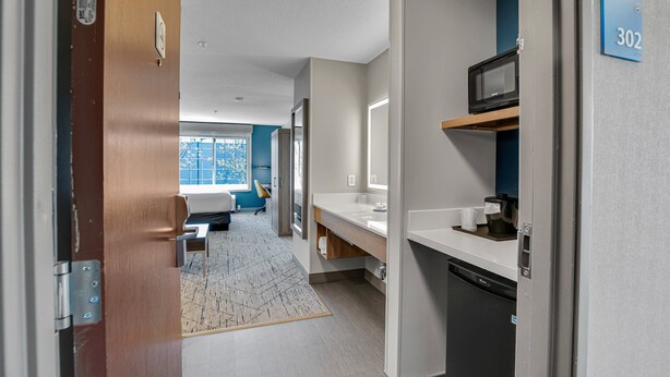 A modern hotel room with a kitchenette, a large window, and a view of the outdoors. - Holiday Inn Express Hotel & Suites Portland-Jantzen Beach by IHG (Portland)
