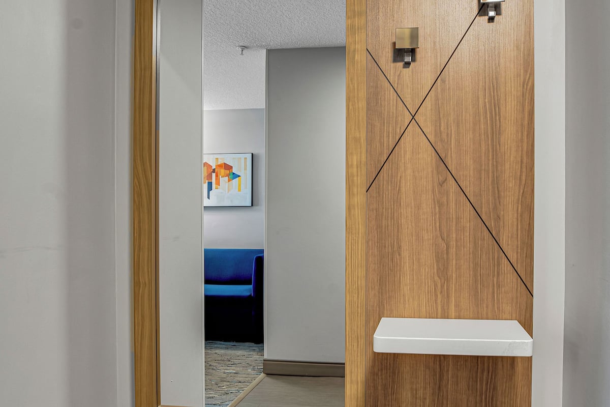 A room with a wooden cabinet, a mirror, and a blue couch in the background.