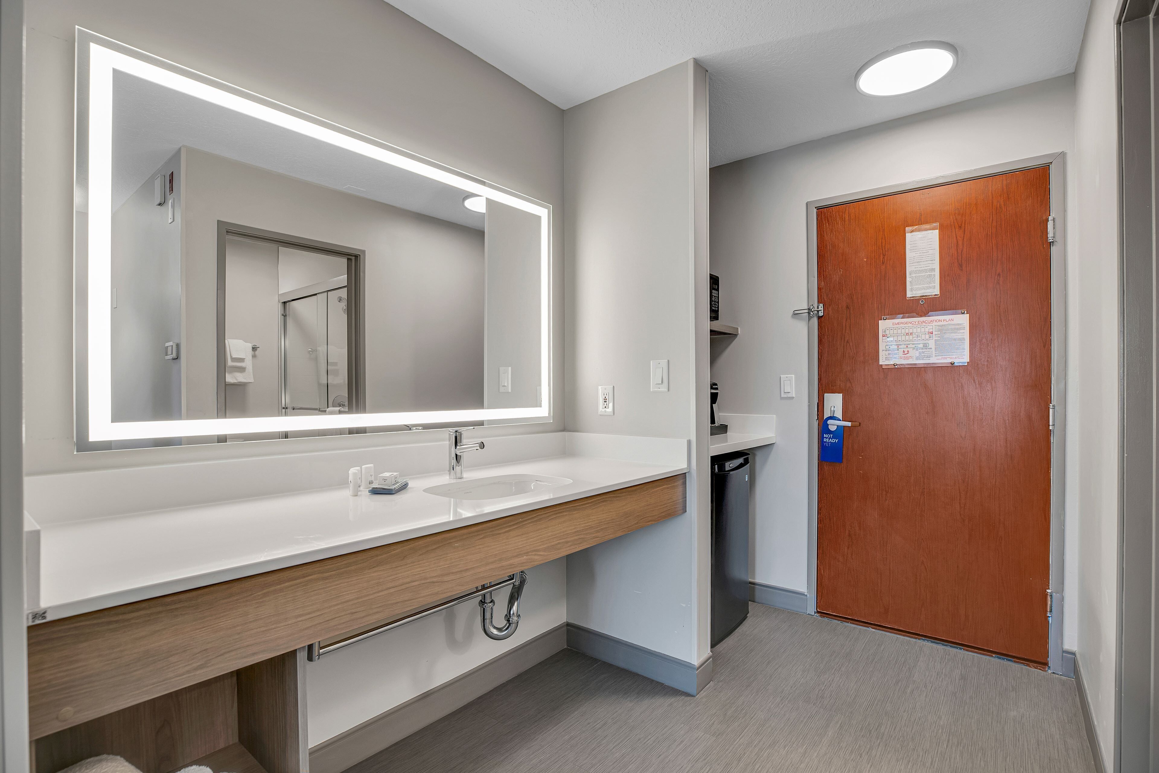 Une salle de bain moderne avec un grand miroir, deux vasques et un meuble-lavabo en bois.