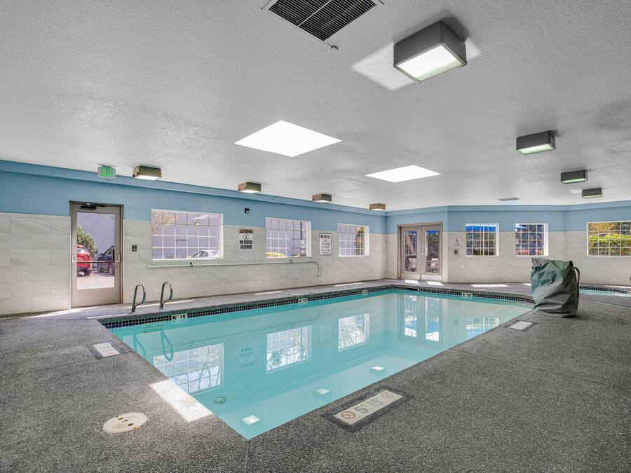 A swimming pool with a tiled floor, clear water, and a blue wall.