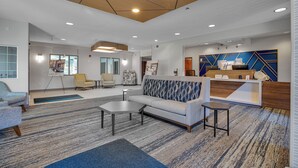 A modern lobby with a sofa, chairs, a reception desk, and a patterned carpet. - Holiday Inn Express Hotel & Suites Portland-Jantzen Beach by IHG (Portland)