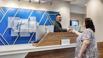 Un mostrador de recepción de hotel con un diseño moderno, que presenta una paleta de colores azul y blanco y una encimera de madera.