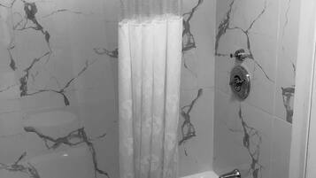 Une salle de bain avec un mur décoré d’un motif imitant le marbre, un rideau de douche, une baignoire et une douchette à main.