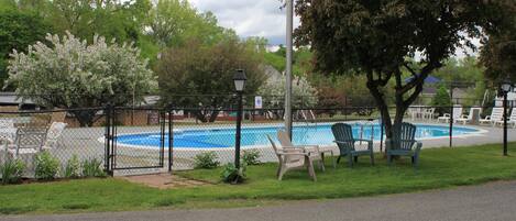 Zona de piscina cercada con sillas y un farol.