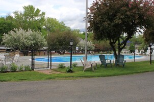 Zona de piscina cercada con sillas y un farol.