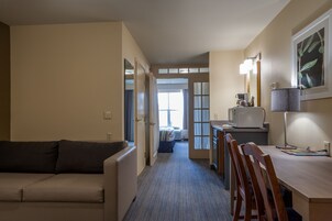 Una habitación de hotel compacta con kitchenette, comedor, sofá y cama.