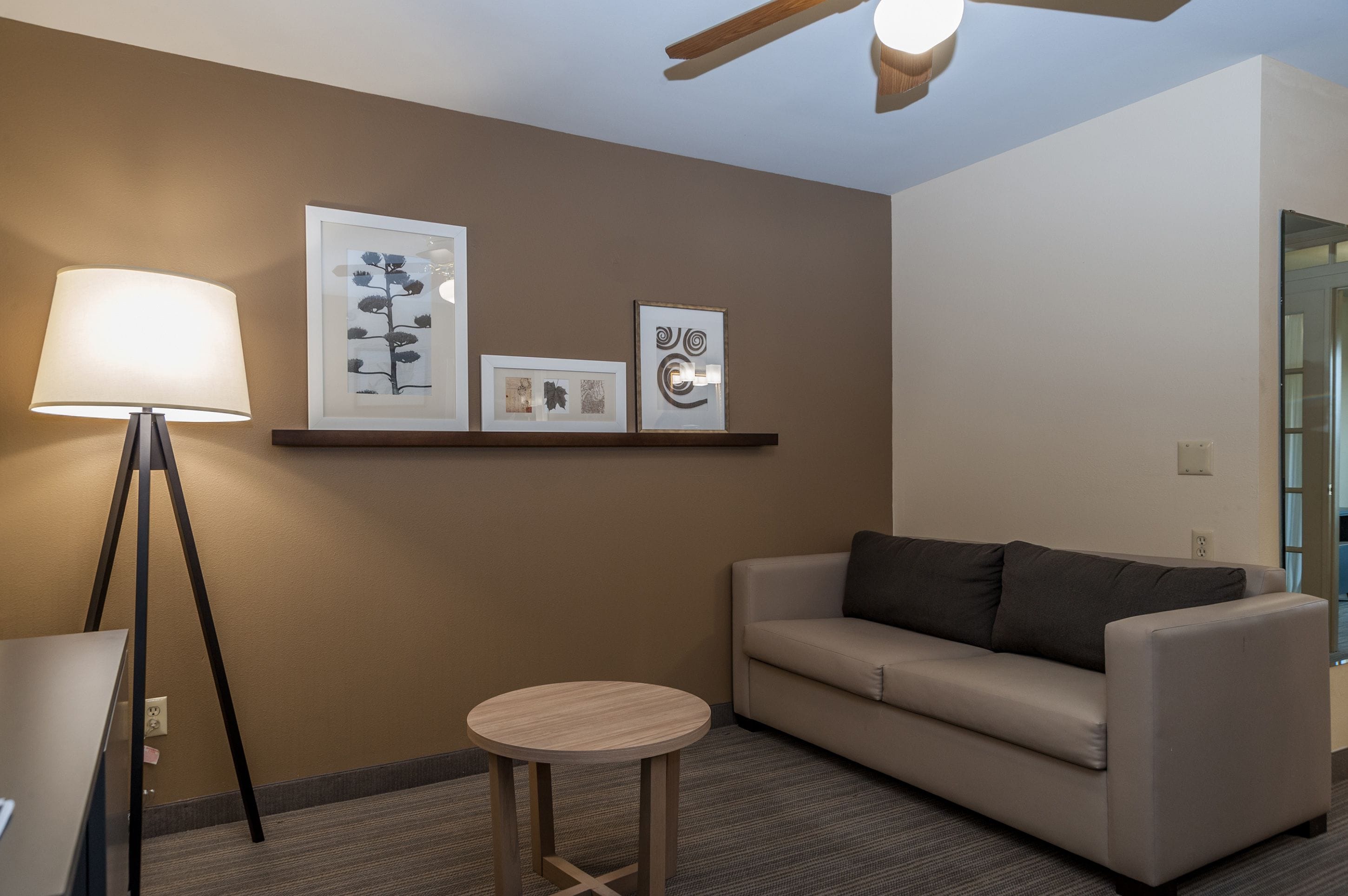 A modern room with a sofa, a small round table, a floor lamp, and wall art.