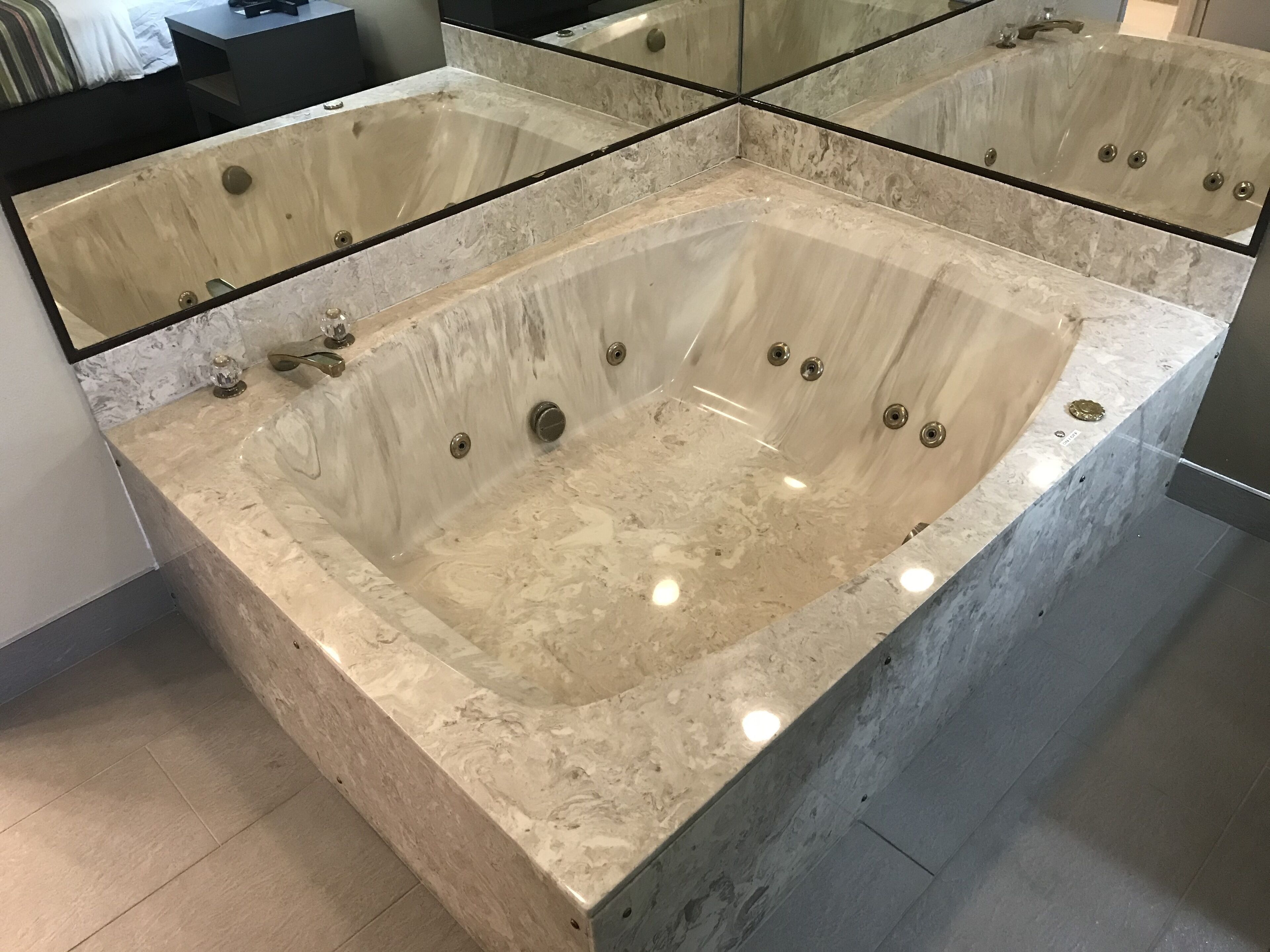 Una amplia bañera independiente con múltiples jets, una encimera de mármol y un diseño de baño moderno.