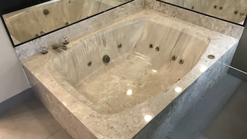 Una amplia bañera independiente con múltiples jets, una encimera de mármol y un diseño de baño moderno.