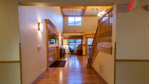 A hotel hallway with wooden flooring, a television, and a staircase. - Country Inn & Suites by Radisson, Milwaukee Airport, WI (Milwaukee)